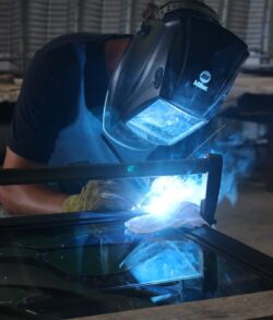 Person welding metal with protective gear and bright sparks.