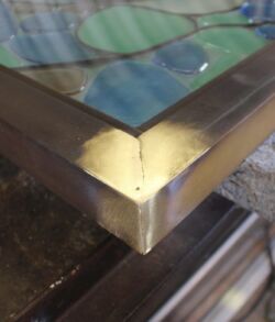 Close-up of a metal frame corner with welding marks on glass.