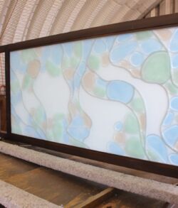 A stained glass panel with abstract shapes and soft colors.