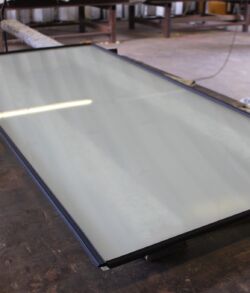 Large glass sheet resting on a metal frame in a workshop.