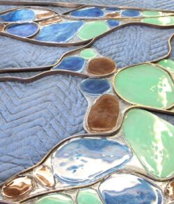 Close-up of glossy, multicolored ceramic tiles with textured blue background.