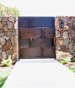 Full view of pedestrian access gate Modern stone and metal gate entrance in a garden.
