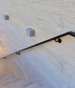 Exterior handrail Minimalist marble wall with small cube decorations and a sleek black handrail.