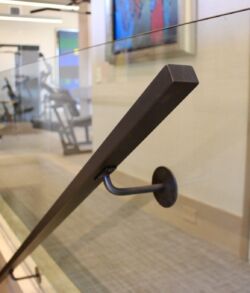 Contemporary brass handrail Close-up of a modern handrail attached to a glass barrier in a gym.