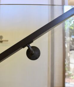 Detail photo of interior handrail Close-up of a black handrail with a blurred door in the background.