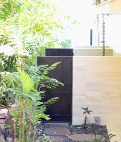 Outdoor shower privacy walls A modern, minimalistic entrance gate surrounded by lush greenery.