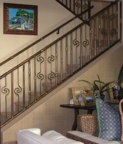 Custom copper handrail with scroll design Elegant staircase with wrought iron railing and cozy living room decor.