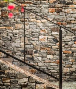 This contemporary banister handrail we named our "disappearing" design Stone staircase with metal railings against a textured brick wall.