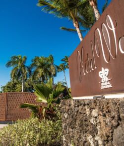 Corten steel entrance gate at the Hotel Wailea on the south shore of Maui Entrance sign of a resort with palm trees and clear blue sky.