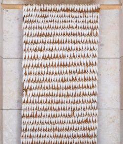 Decorative wall hanging with natural seed pods on a wooden rod.