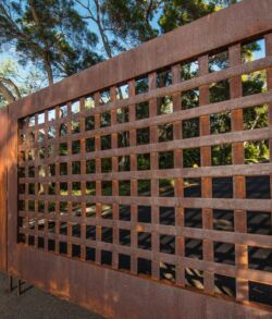 Rusty metal gate with square grid pattern outdoors.