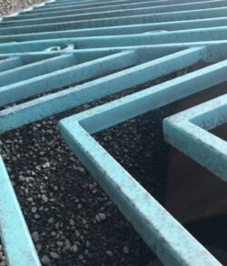 Close-up of a blue metal grate over gravel.