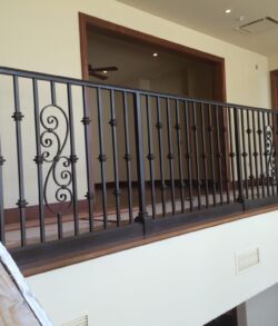 Black metal railing with decorative swirls in a hallway.