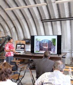 People attending a presentation with a screen showing an architectural design.