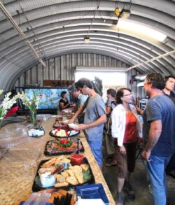People serving themselves food at a buffet line in a covered outdoor area.