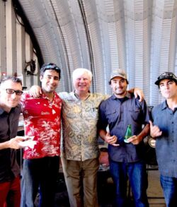 Post presentation group shot Five men posing together inside a large industrial space.