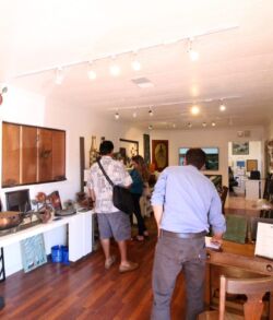 Inside Padilla Designs showroom People exploring an art gallery with paintings and sculptures.