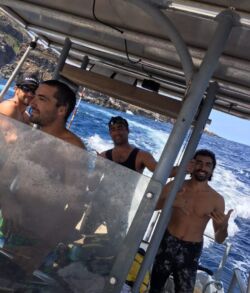Three men on a boat in the ocean on a sunny day.