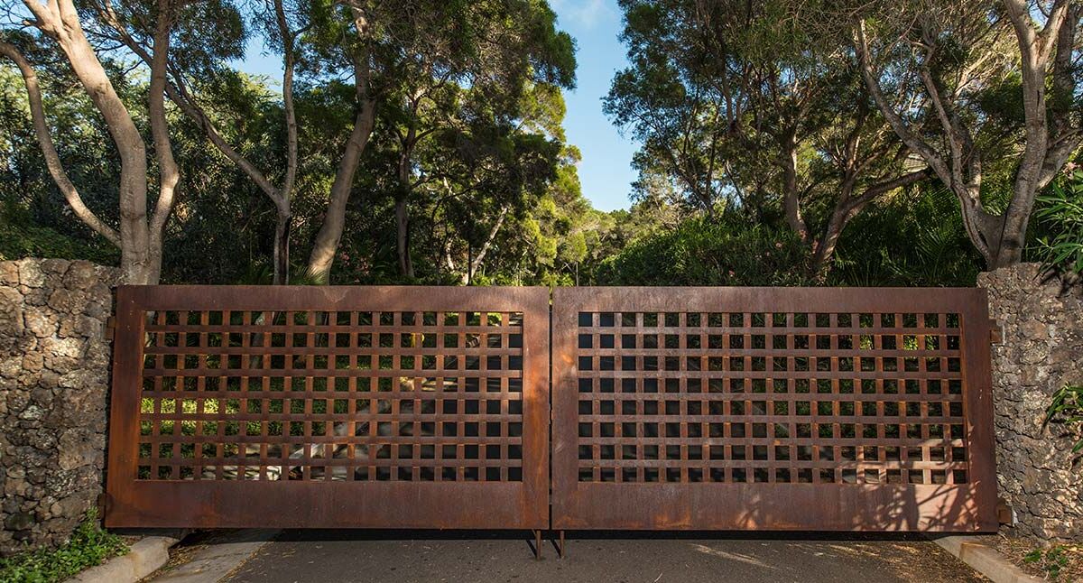 Rustic wooden lattice gate surrounded by trees under a clear sky.