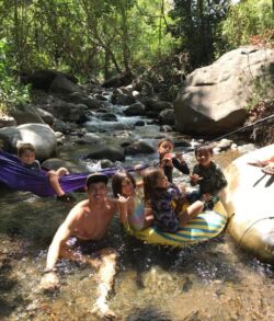 A group of people enjoying a stream with an inflatable tube on a sunny day.