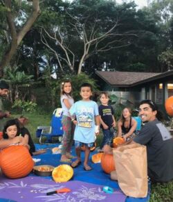 Family carving pumpkins outdoors in a backyard.