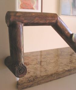 Kiawe look engraved copper hand rail Close-up of a wooden handle attached to a marble surface.