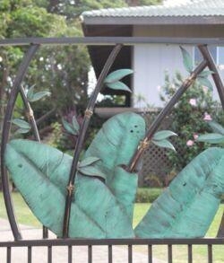 Drive gate insert Large green hand sculpture behind a black fence in front of a building.