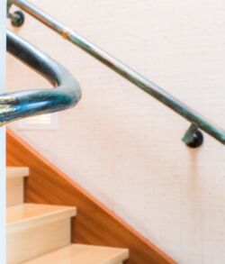 Wooden staircase with metal handrails and beige walls.