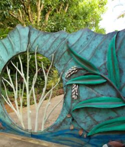 A green dragon sculpture with an open mouth and visible teeth in a garden.