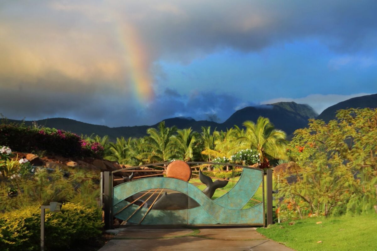 Turquoise sculpted gate beneath mountain rainbow