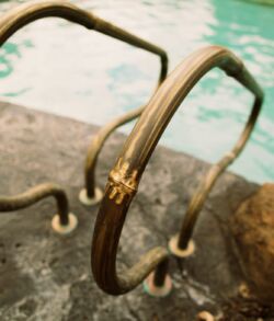Brass bamboo pool railing with highlights Rusty metal handrails by a swimming pool.