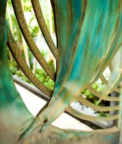 Close-up of vibrant teal and green fabric draped over a wooden chair outdoors.