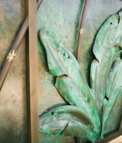 Close-up of an ornate green metal leaf design on a decorative surface.