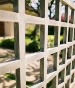 Close-up of a white metal grid fence with a blurred background.
