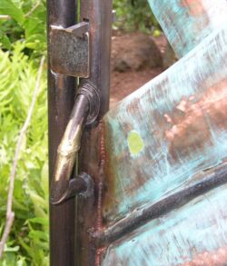 Close-up of a rusty hinge on a weathered metal door with patina.