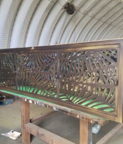Decorative metal panel with intricate laser-cut leaf designs.