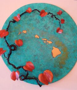 A round teal cake decorated with a red flower vine and golden patterns.