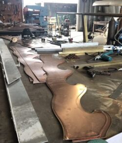 Large metal sheets with cut-out patterns in a workshop.