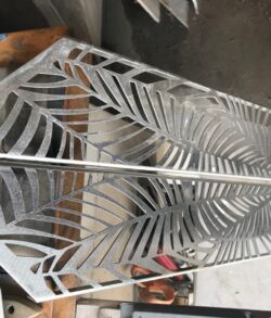 Metal panel with intricate palm leaf design, ready for installation.