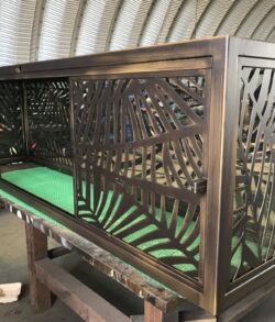 Intricately carved wooden crib with green bedding inside a sheltered structure.