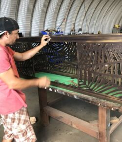 Man crafting an intricate wooden panel in a workshop.