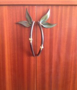 Decorative leaf-shaped handles on wooden cabinet doors.