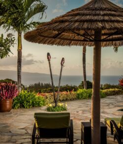 Pool side Tiki torch set Relaxing patio with a view of the ocean under a thatched umbrella.