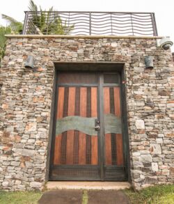 Rustic stone entryway with a wooden door featuring a metal dolphin design.