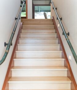 Bright, modern staircase with wooden steps and handrails on both sides.