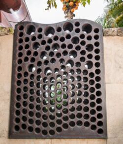 Outdoor privacy shower window A perforated metal sheet with a curved shape and multiple holes.