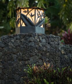 Modern outdoor lantern atop a stone wall during dusk.
