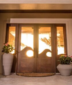 Elegant wooden double doors with glass panels, flanked by large potted plants.
