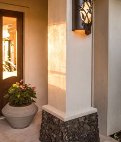 Warm outdoor wall lighting beside a potted plant.