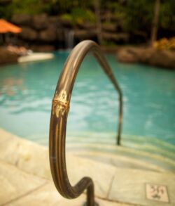 Close-up of a rusty pool handrail with water in the background.